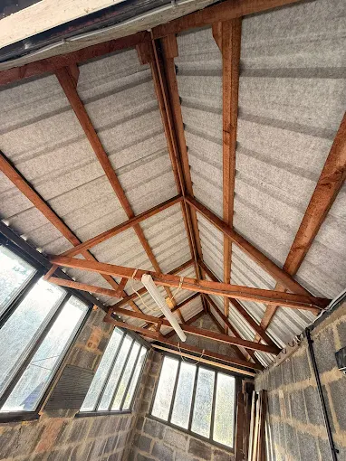 Asbestos cement roof sheets viewed from inside an outbuilding before removal